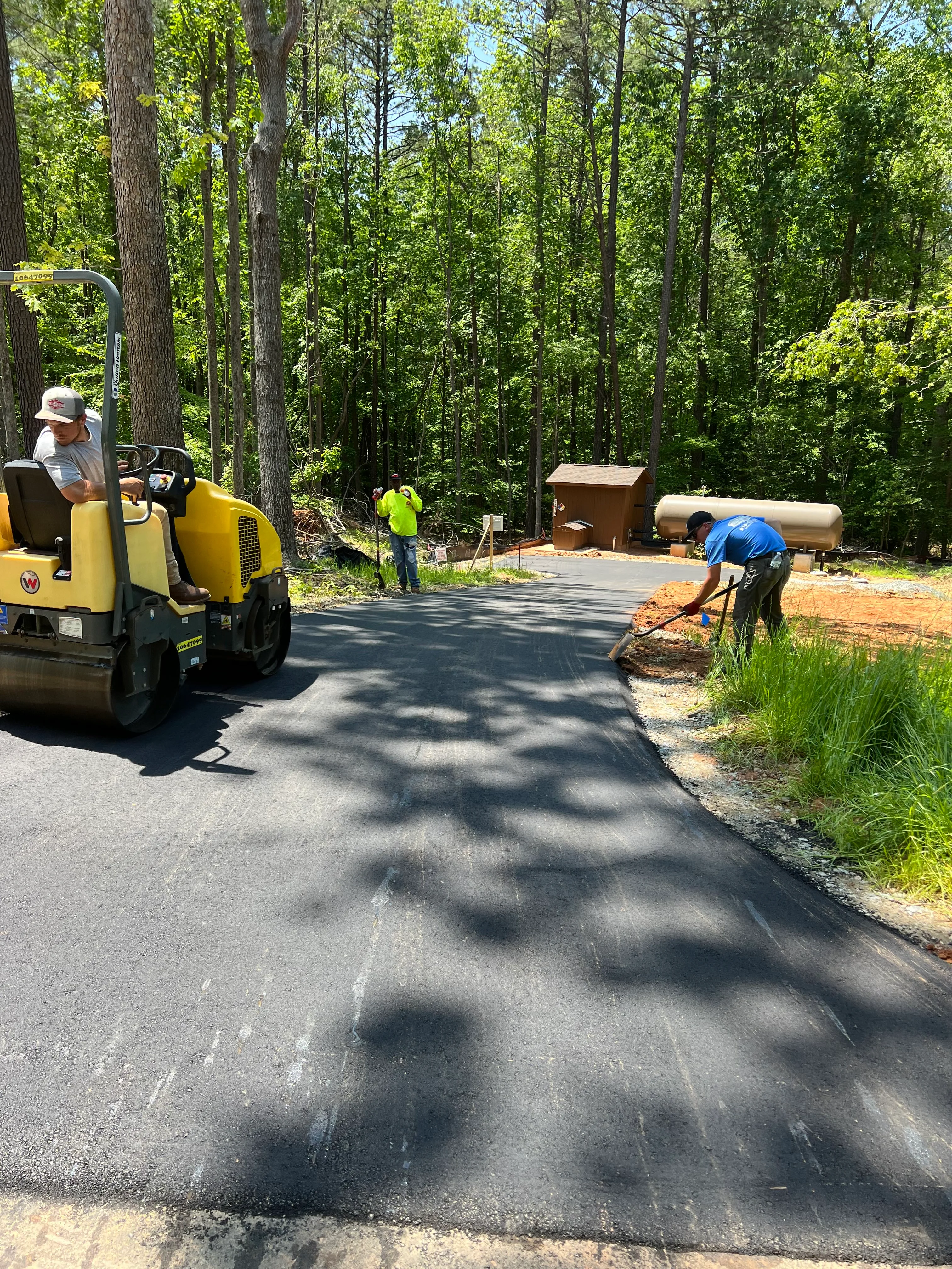 Professional asphalt paving crew laying fresh asphalt on a residential driveway